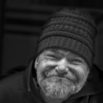a black and white stunning street portrait of an elderly man with a pleasant smile